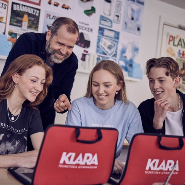 Elever och lärare kollar på en laptop