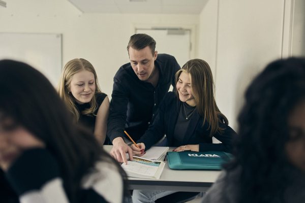 Lärare hjälper elever med uppgift.