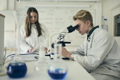 Elev studerar prov i mikroskop, laboratorium.