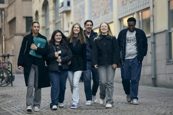 Grupp glada elever promenerar utomhus.