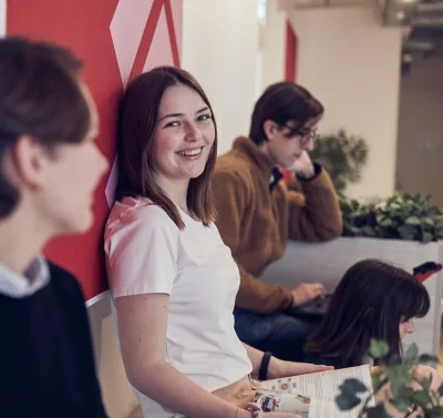 Elev sitter på en bänk i skolan och ler in i kameran.
