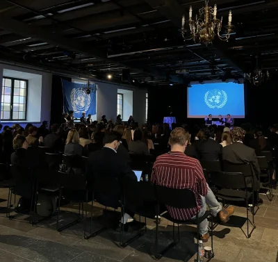 Elever sitter med sina ryggar mot kameran och blickar framåt scenen på FN-rollspelet.