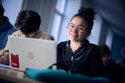 Elev med glasögon framför dator.