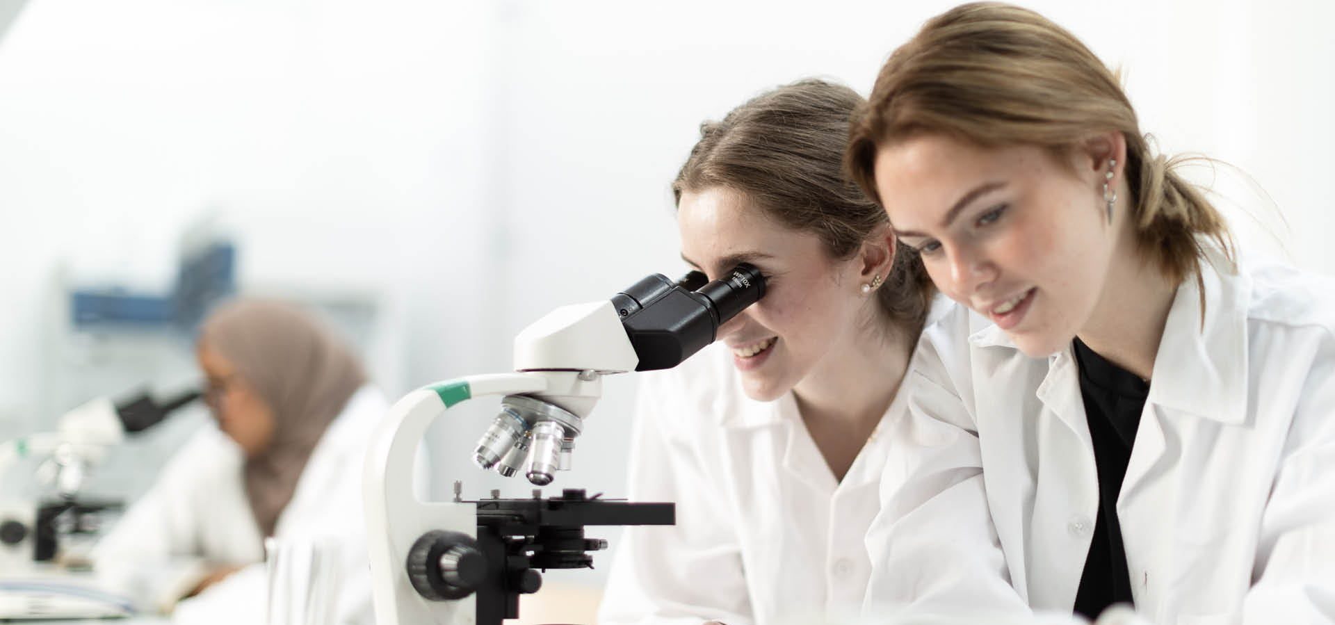 Elever i vita rockar använder ett mikroskåp