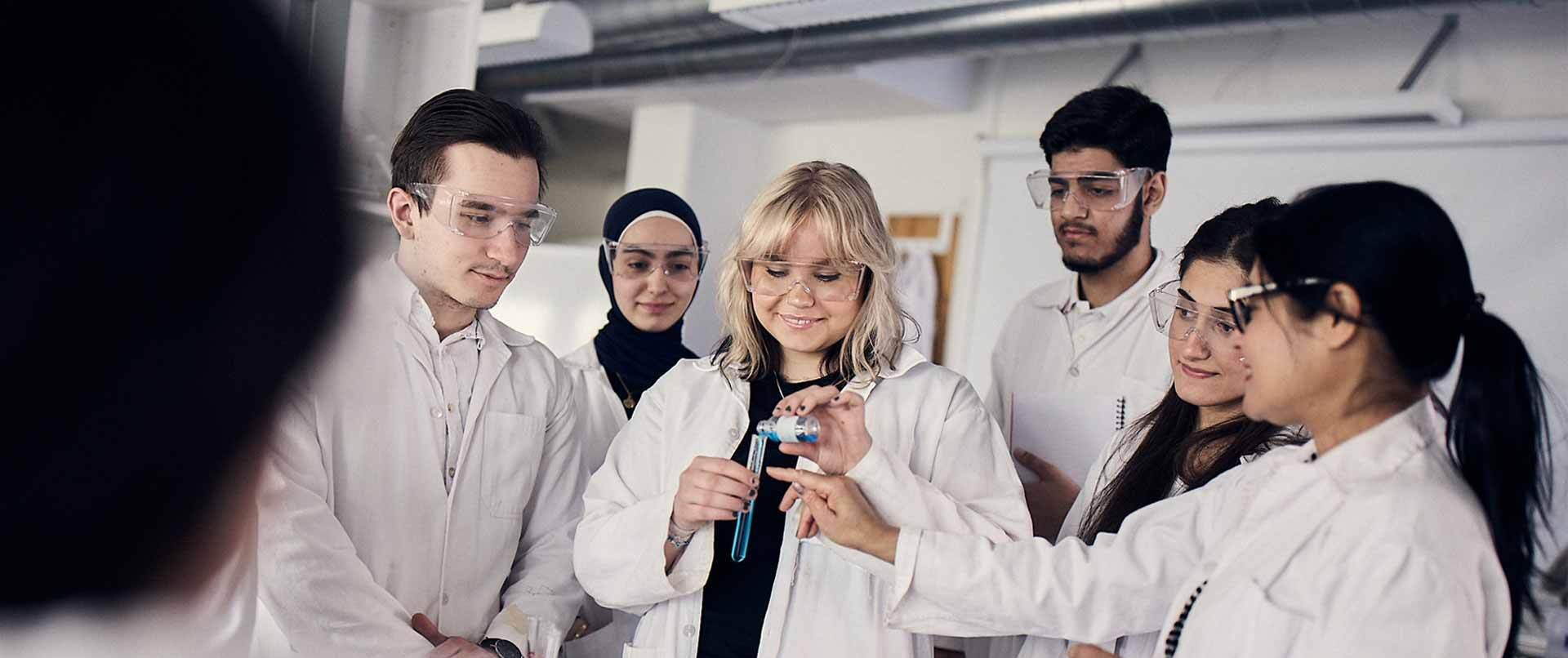 Elever i vita rockar och skyddsglasögon laborerar