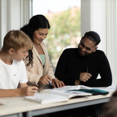 Lärare hjälper två elever med en uppgift i ett klassrum
