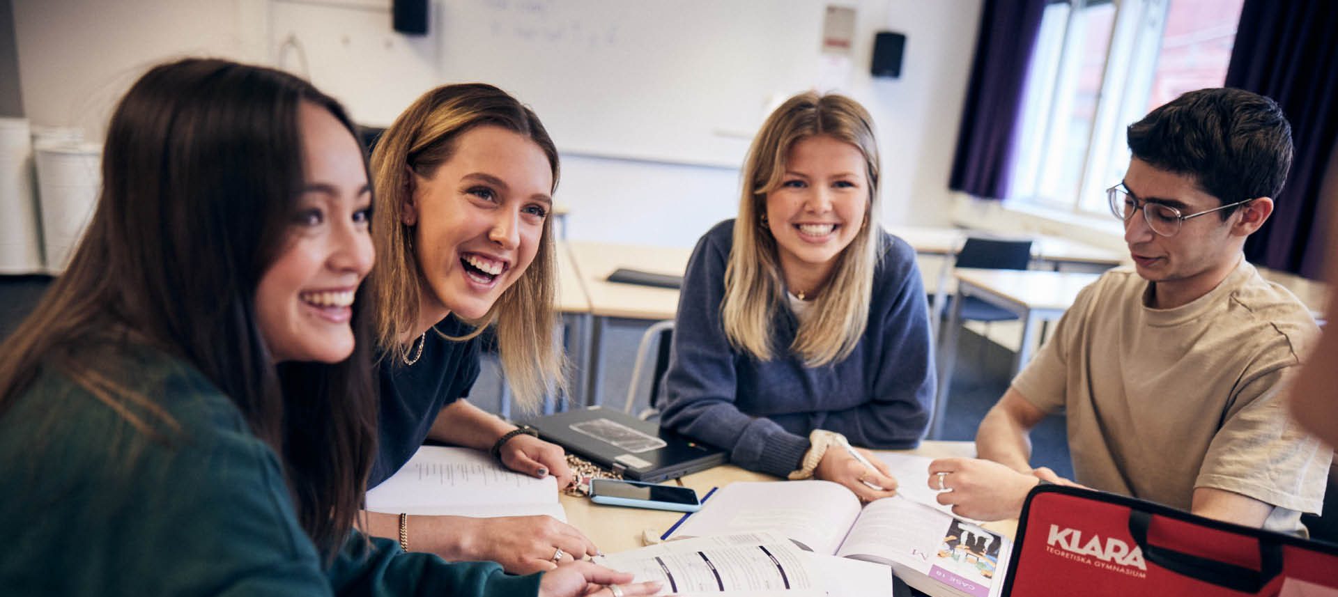 Elever sitter runt ett bord och arbetar med ett grupparbete