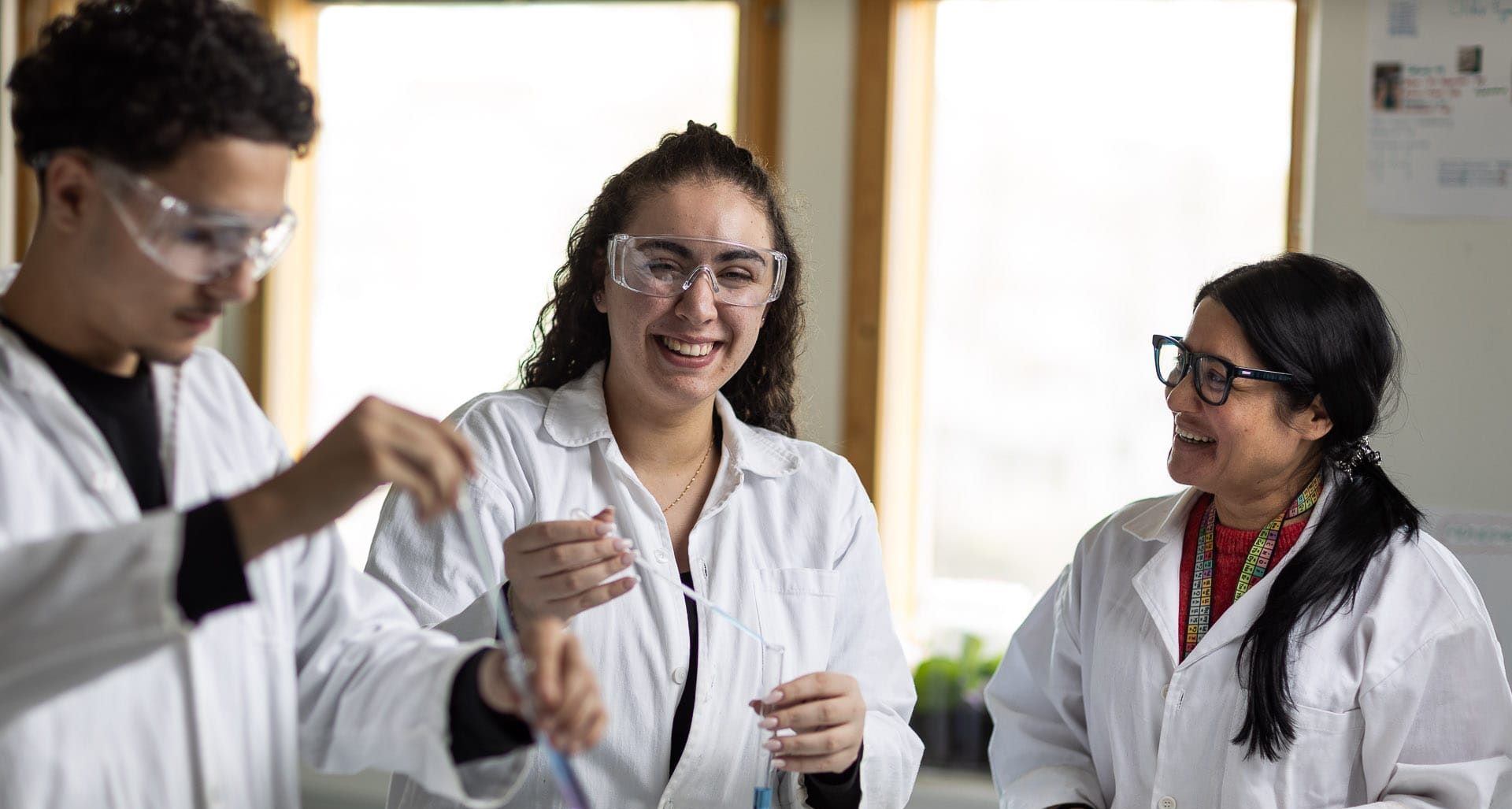 Glada elever labbar med vita labbrockar på sig.