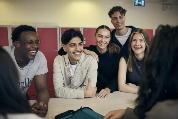 Fem glada elever skrattar och ler in i kameran.