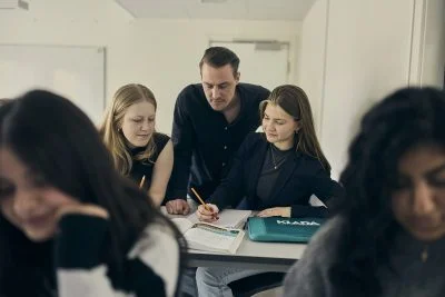 Lärare hjälper två elever med uppgift.