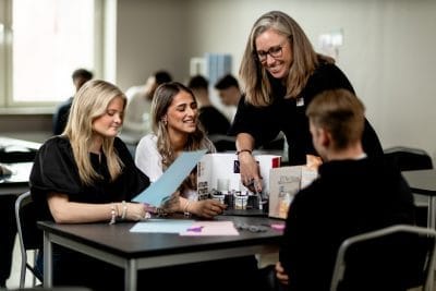 Elever har lektion och lärare hjälper till.