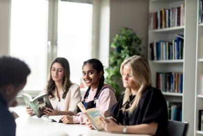 Elever läser bok i biblioteket.