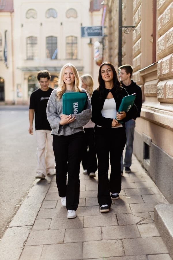 Två elever går mot kameran utomhus.